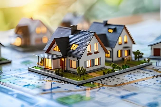 Miniature house models arranged on a detailed blueprint map, symbolizing residential property development planning, real estate site acquisition, and neighborhood master planning.