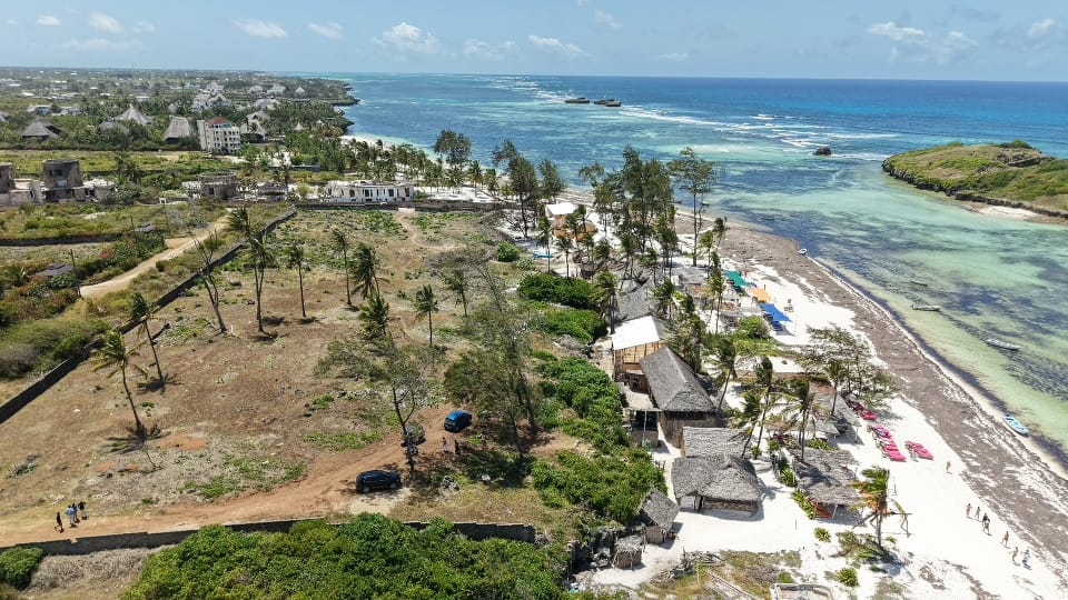Aerial view of vacant beachfront land for sale in Watamu, Kenya, showcasing prime oceanfront development plots next to luxury holiday resorts and the turquoise Indian Ocean reef.