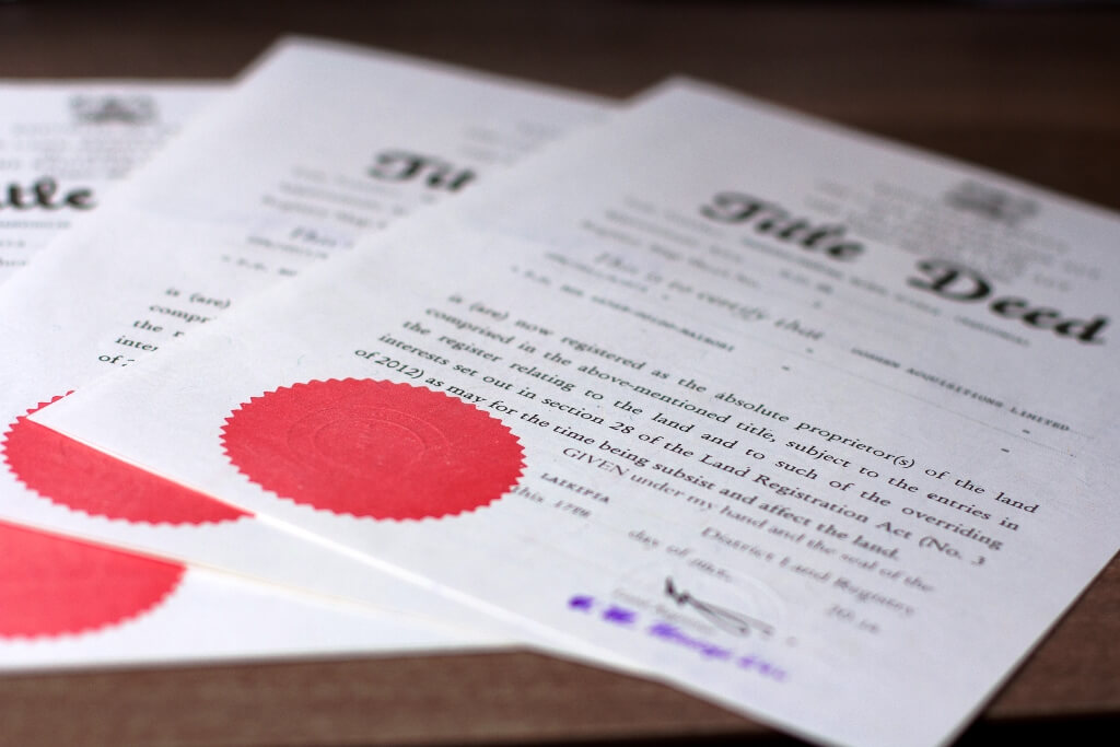 alt="Close-up of official Kenyan Land Registration Act Title Deed documents showing a red embossed seal stamp, illustrating absolute proprietorship verification and real estate due diligence.